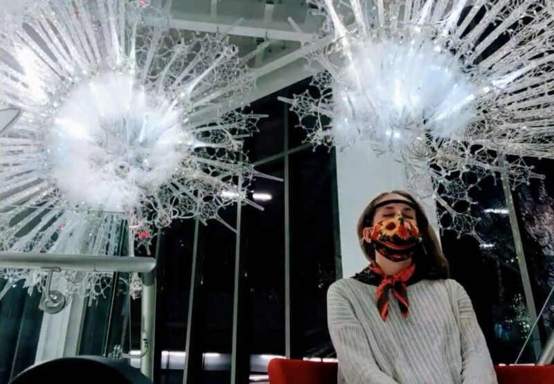 A woman sits beneath the Amatria sculpture wearing a Muse EEG Headset